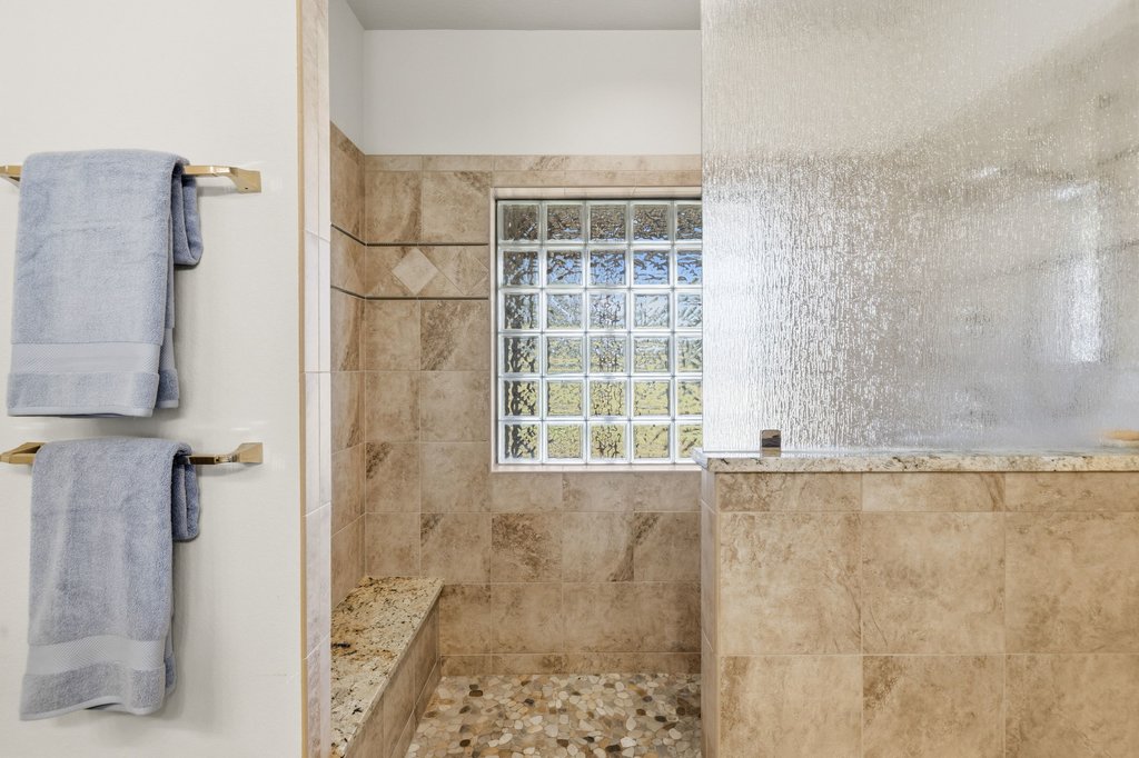 1101 Windy Hills Road Dripping Springs, TX 78620 - Photo 23 of 40 A glass block window illuminates this shower with a tiled bench and pebble-stone floor.