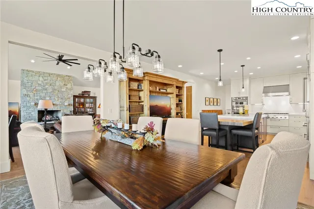 a view of a dining room and livingroom with furniture wooden floor a rug a fireplace and a chandelier