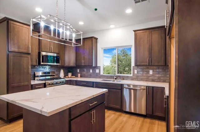 a kitchen with stainless steel appliances granite countertop a sink stove and refrigerator