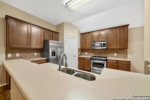 a kitchen with stainless steel appliances granite countertop a sink stove microwave and refrigerator