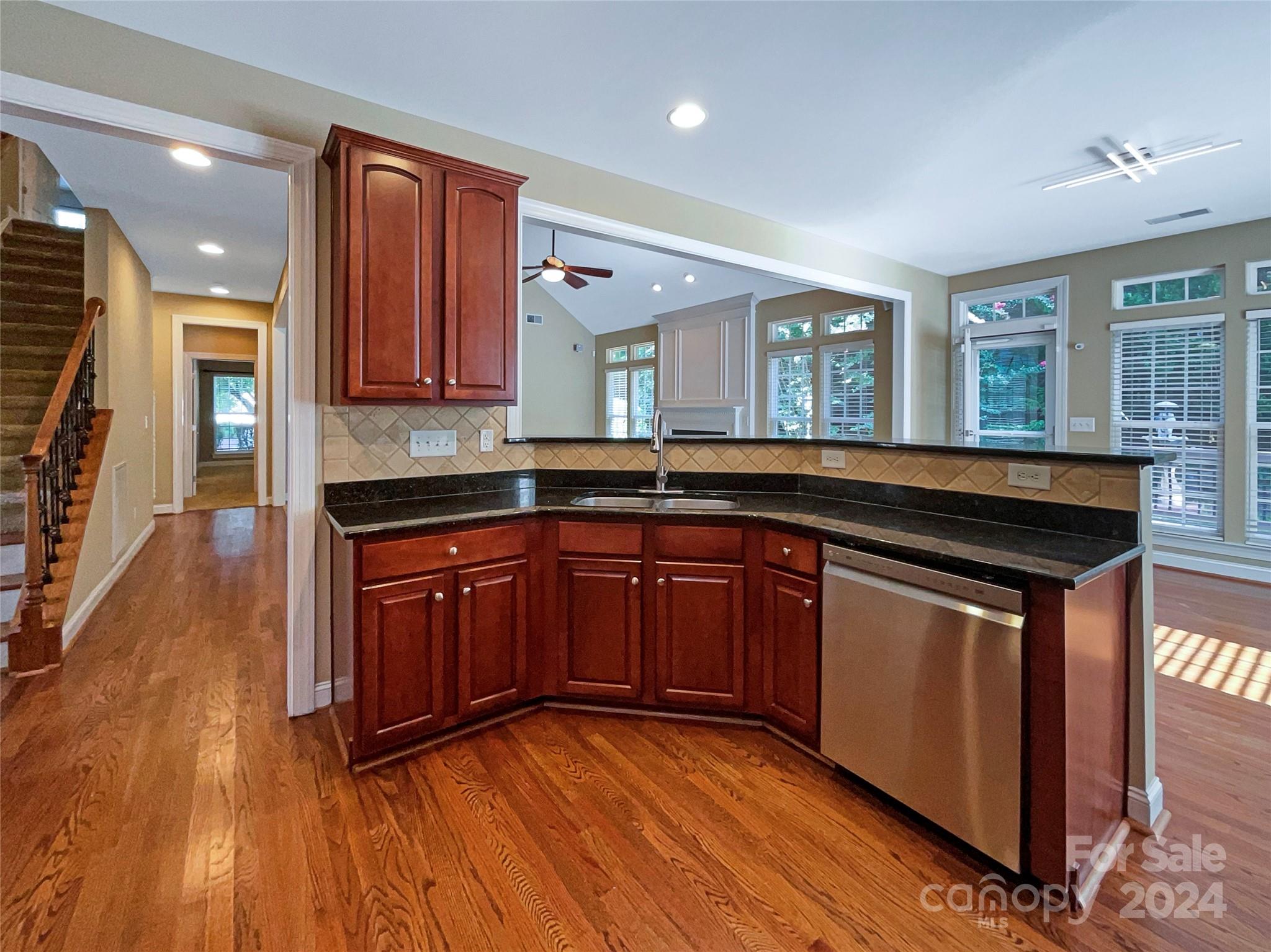 604 Panthers Way Fort Mill, SC 29708 - Photo 14 of 24 a kitchen with granite countertop wooden floors wooden cabinets and sink