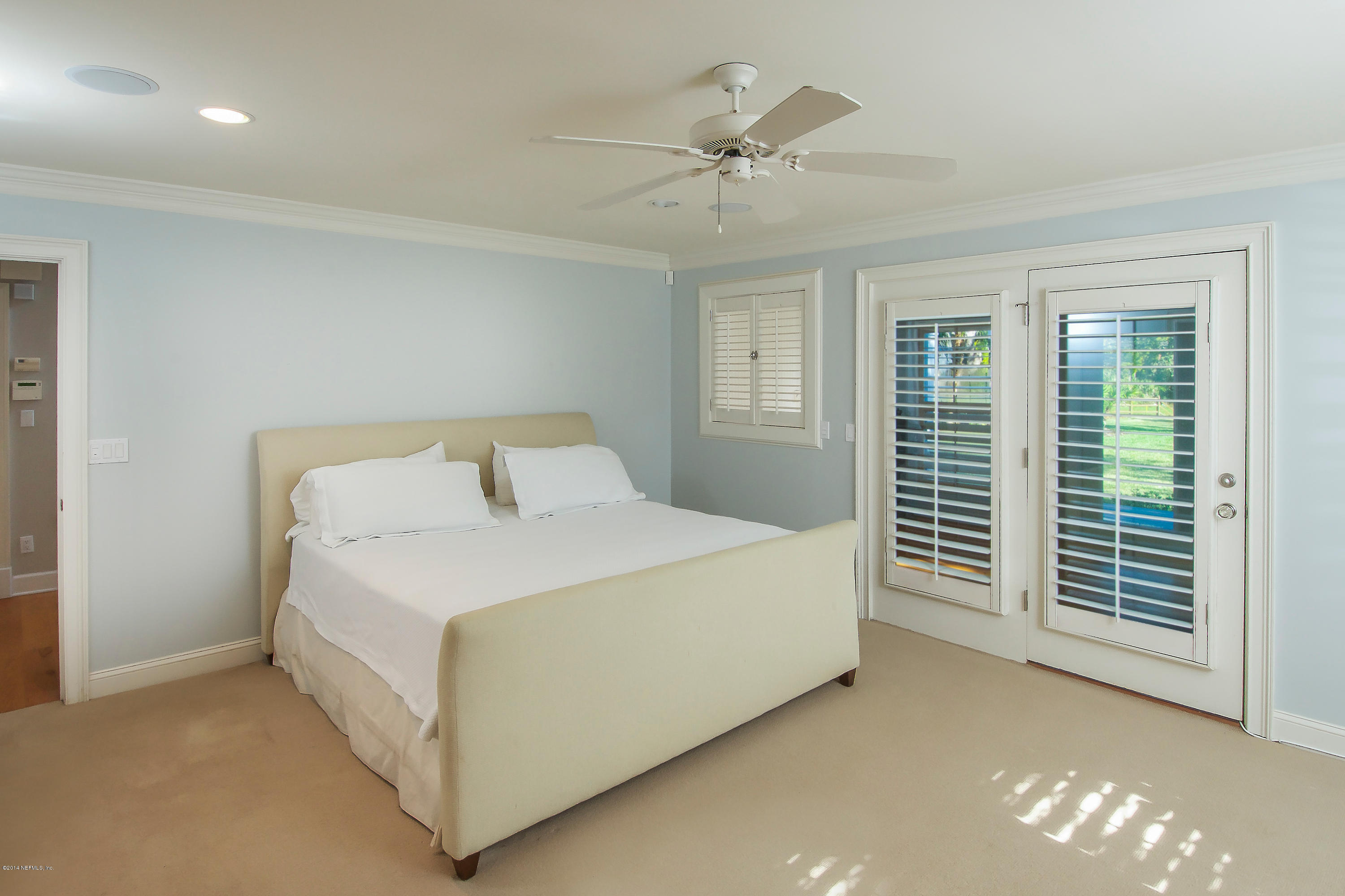 1122 Neck Road Ponte Vedra Beach, FL 32082 - Photo 15 of 35 a bed sitting in a bedroom next to a window and a chandelier
