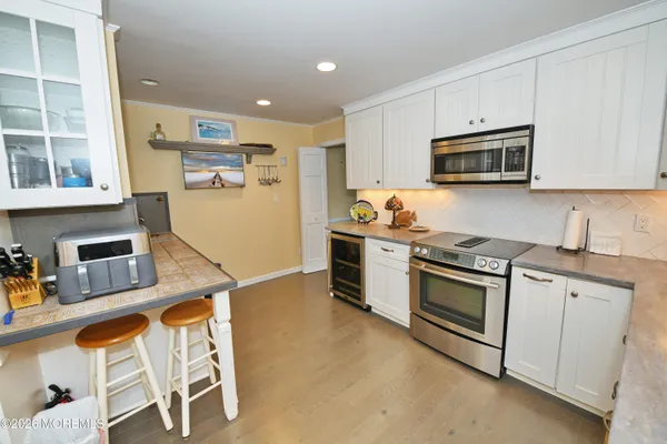 a kitchen with stainless steel appliances granite countertop a stove top oven a sink dishwasher and white cabinets with wooden floor