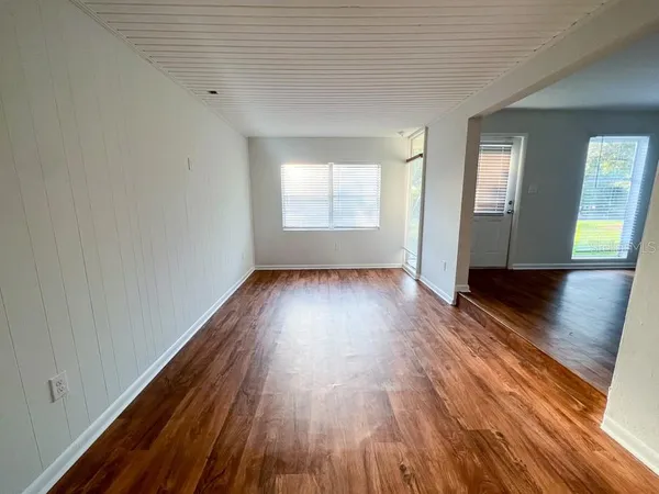 an empty room with wooden floor and windows
