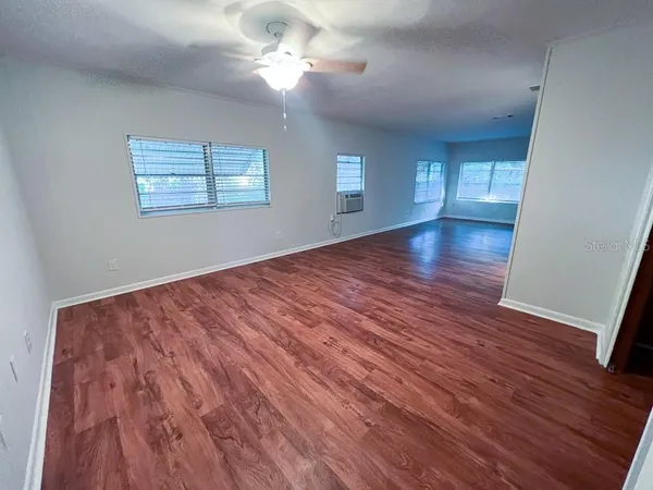 a view of empty room with wooden floor and fan