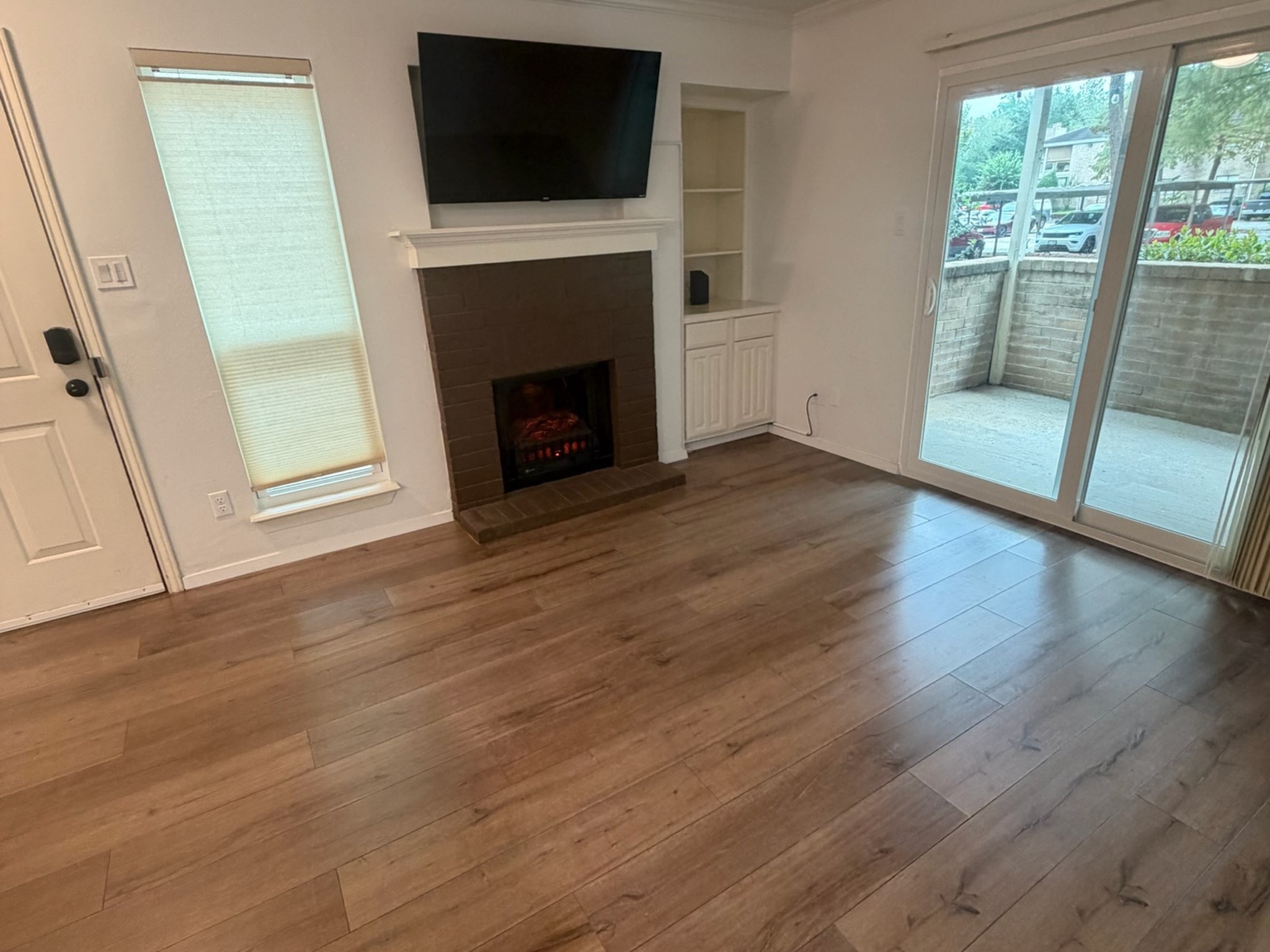 3500 Tangle Brush Drive, Unit 65 Spring, TX 77381 - Photo 11 of 20 New electric fireplace with built-in storage, crown molding, wood-look floors, and a 2026 patio door opening to the private covered patio.