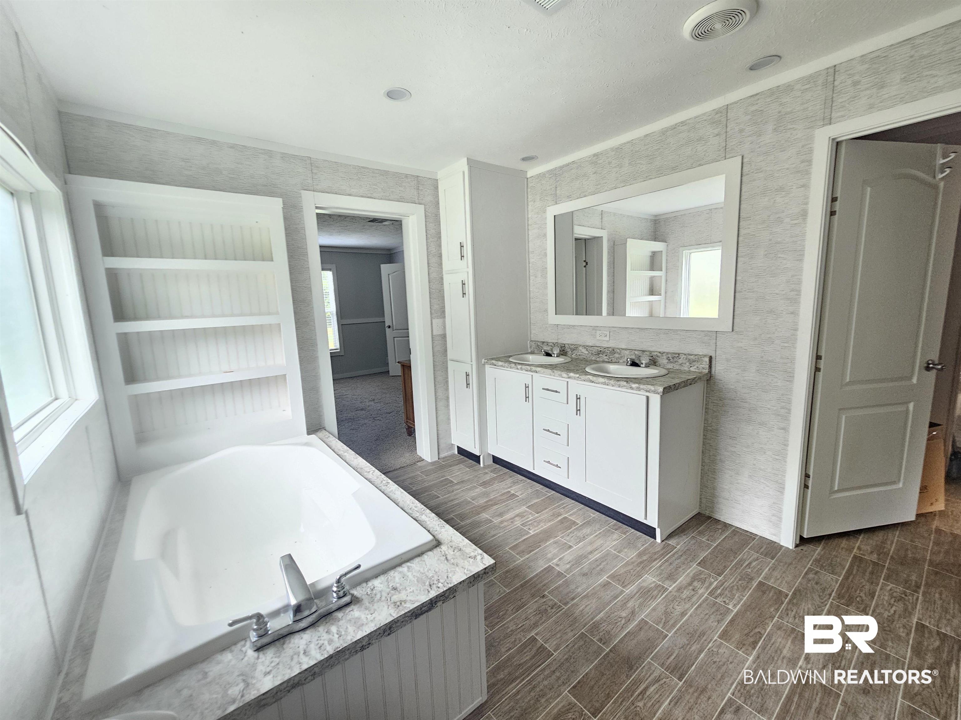 1863 Wait Road Monroeville, AL 36460 - Photo 8 of 38 Bathroom featuring built in features, dual vanity, hardwood / wood-style flooring, and a tub