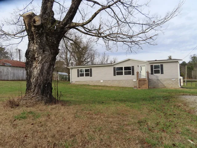 a view of a yard in front of a house with large trees