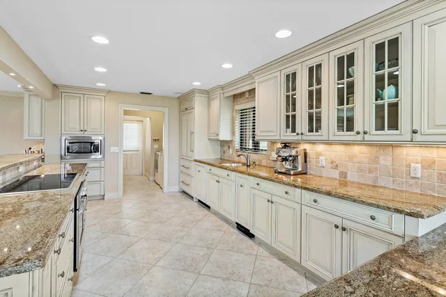 a large kitchen with kitchen island granite countertop a sink and white cabinets