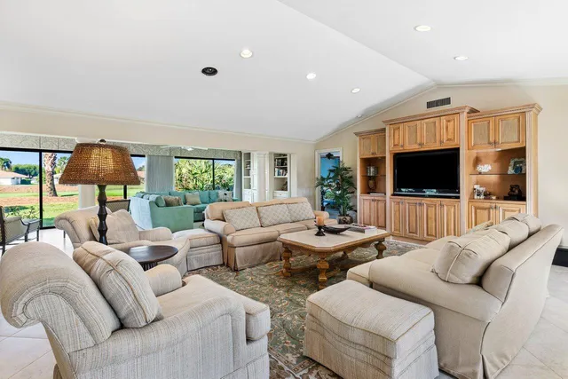 a living room with furniture a flat screen tv and a floor to ceiling window