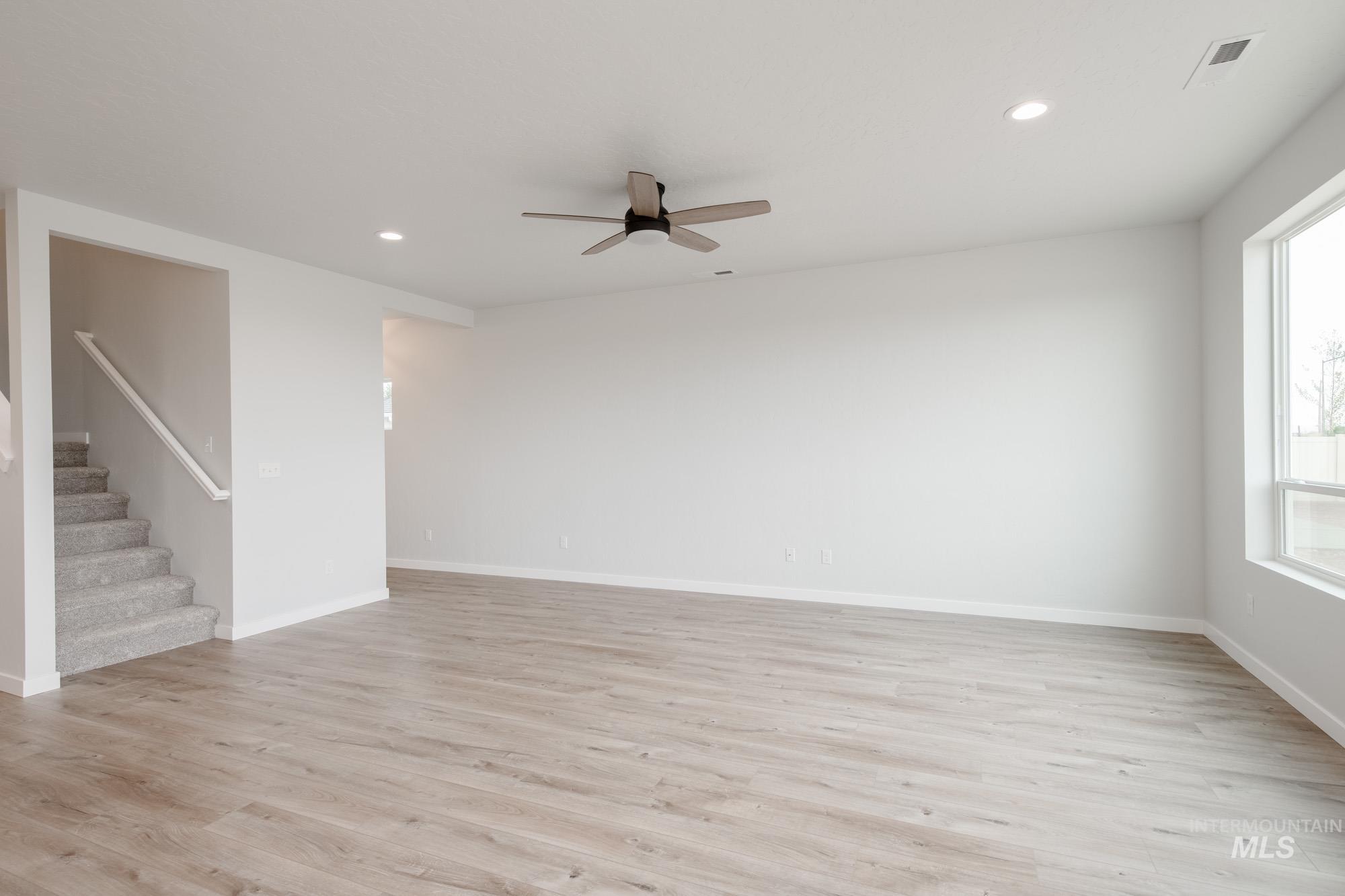 4155 North Delphi Avenue Meridian, ID 83646 - Photo 11 of 24 Spare room featuring light wood-style floors, ceiling fan, recessed lighting, and stairway