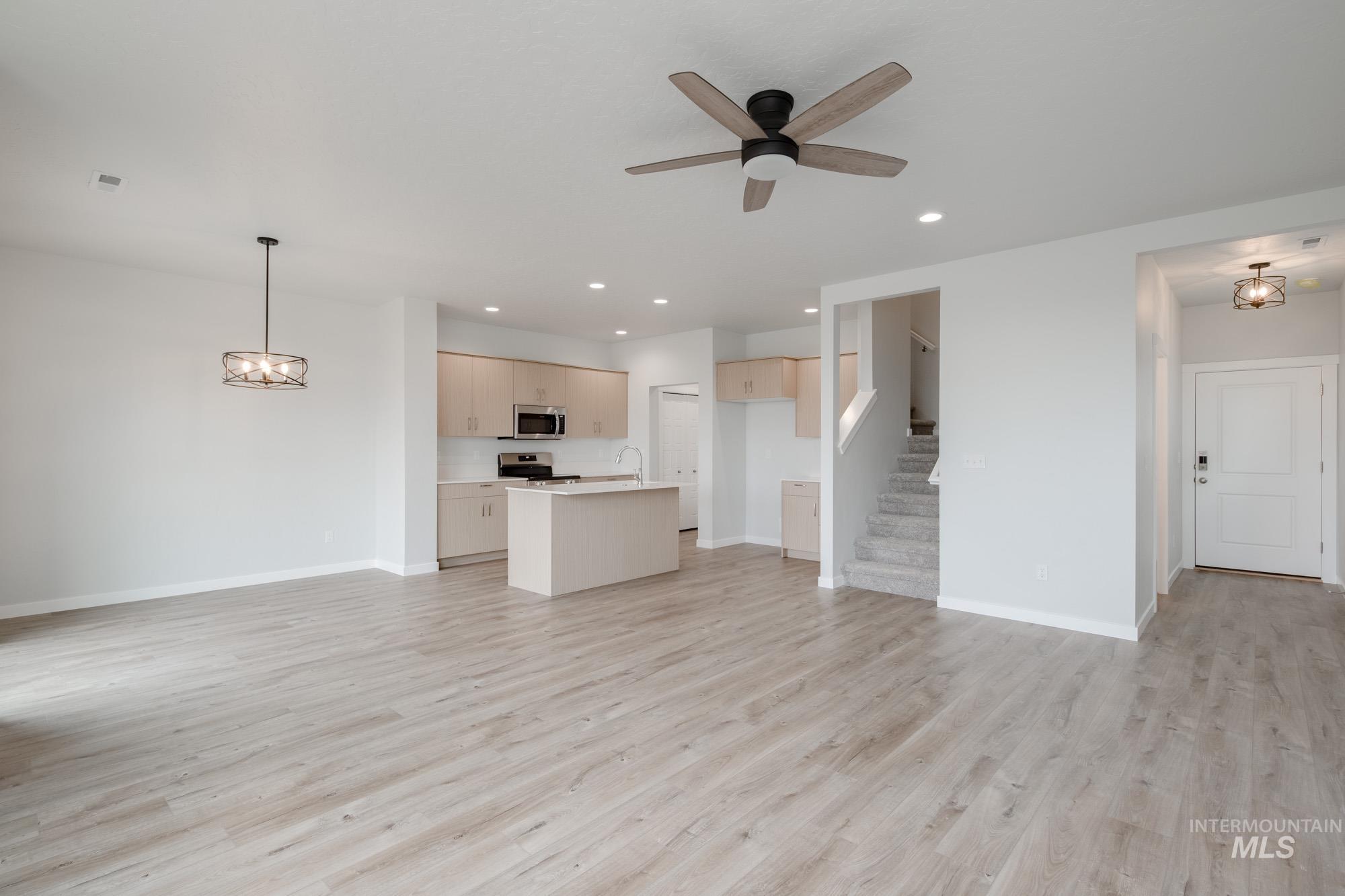 4155 North Delphi Avenue Meridian, ID 83646 - Photo 12 of 24 Unfurnished living room featuring light wood-type flooring, recessed lighting, stairway, a ceiling fan, and a chandelier