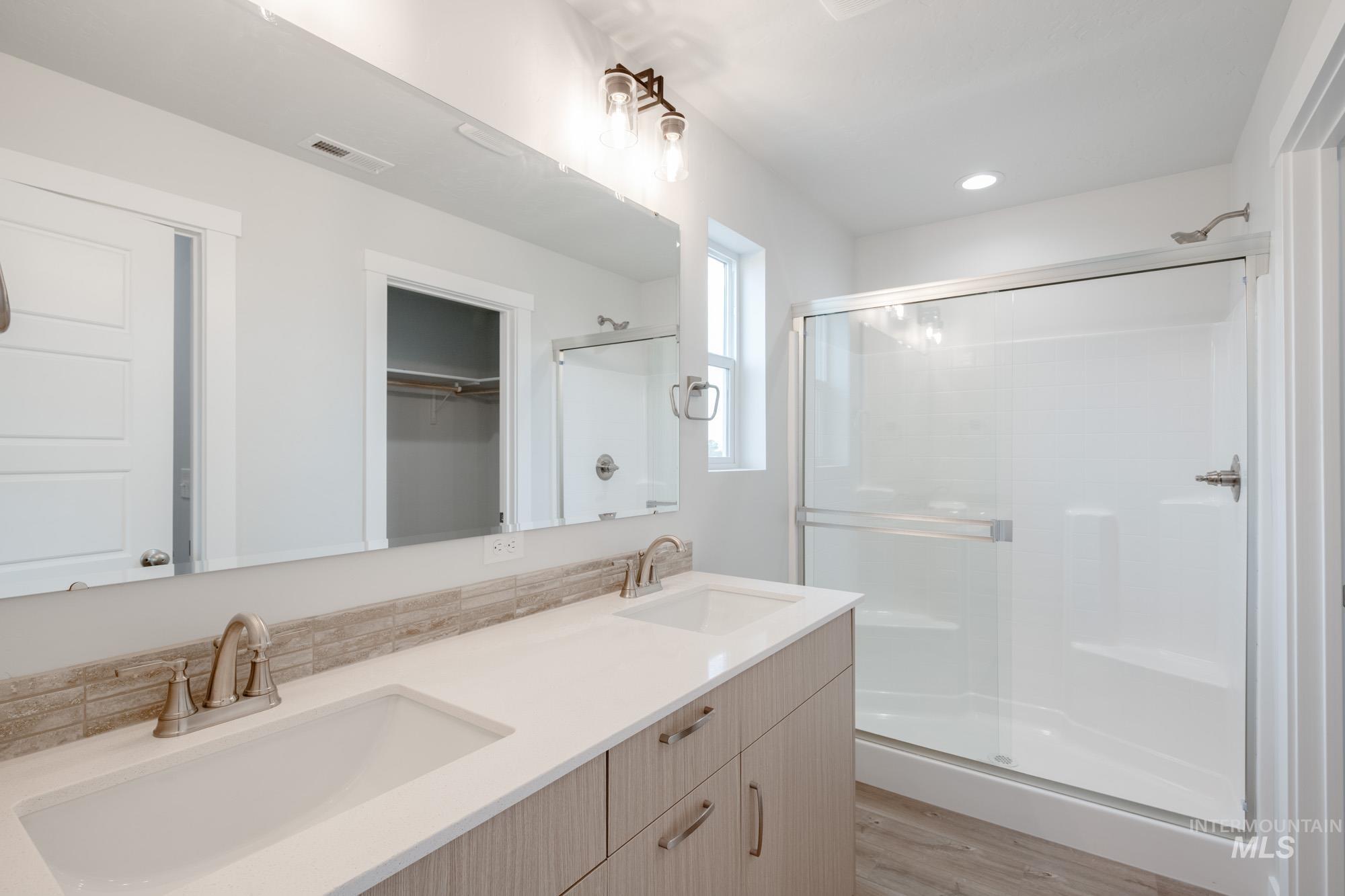 4155 North Delphi Avenue Meridian, ID 83646 - Photo 15 of 24 Bathroom with a spacious closet, a shower stall, double vanity, light wood-style flooring, and recessed lighting