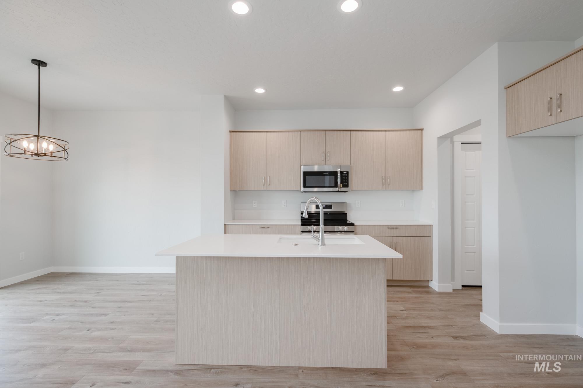 4155 North Delphi Avenue Meridian, ID 83646 - Photo 4 of 24 Kitchen with stainless steel appliances, a center island with sink, light wood-style floors, decorative light fixtures, and recessed lighting