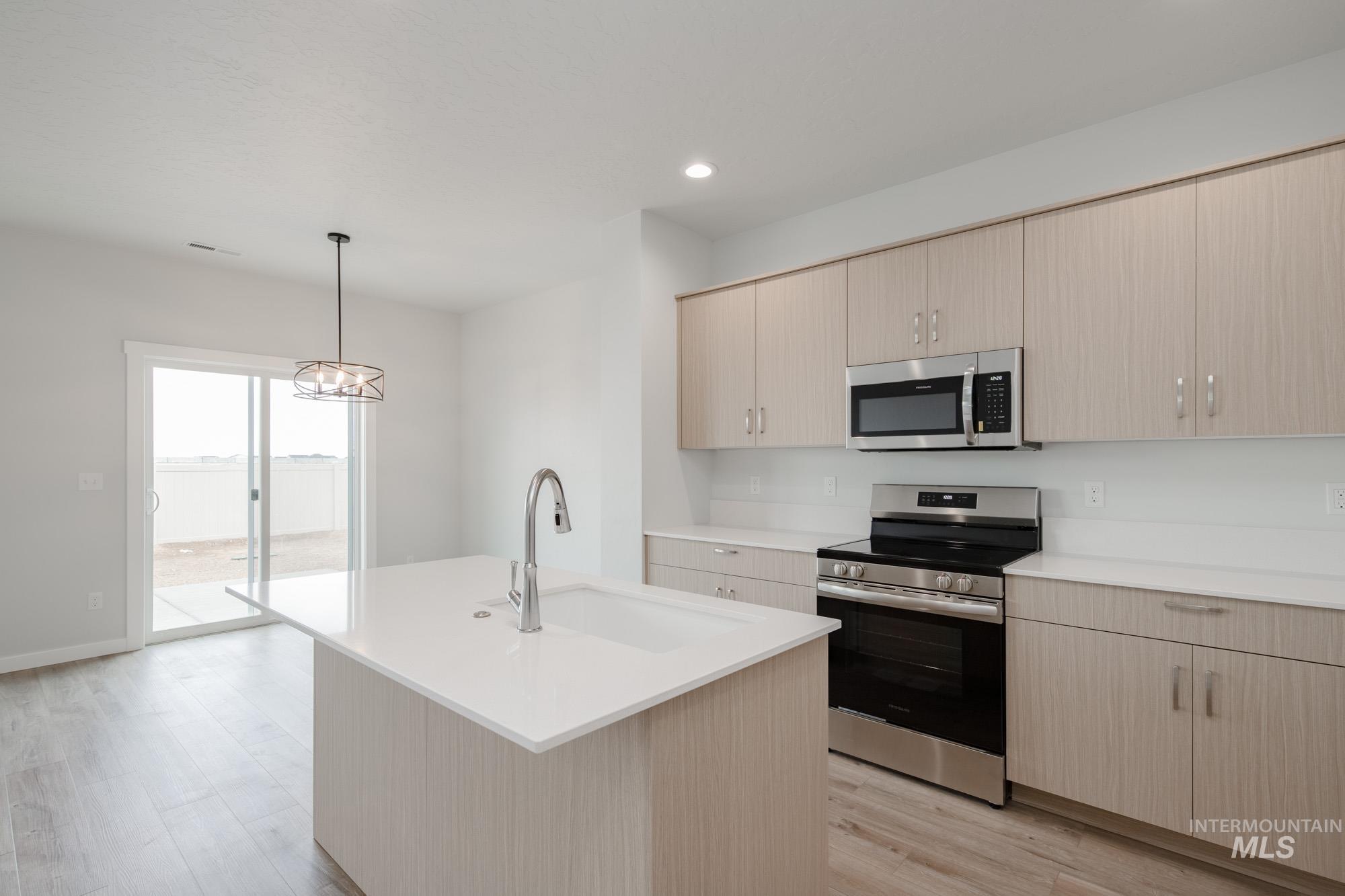 4155 North Delphi Avenue Meridian, ID 83646 - Photo 6 of 24 Kitchen featuring light brown cabinets, appliances with stainless steel finishes, decorative light fixtures, recessed lighting, and an island with sink