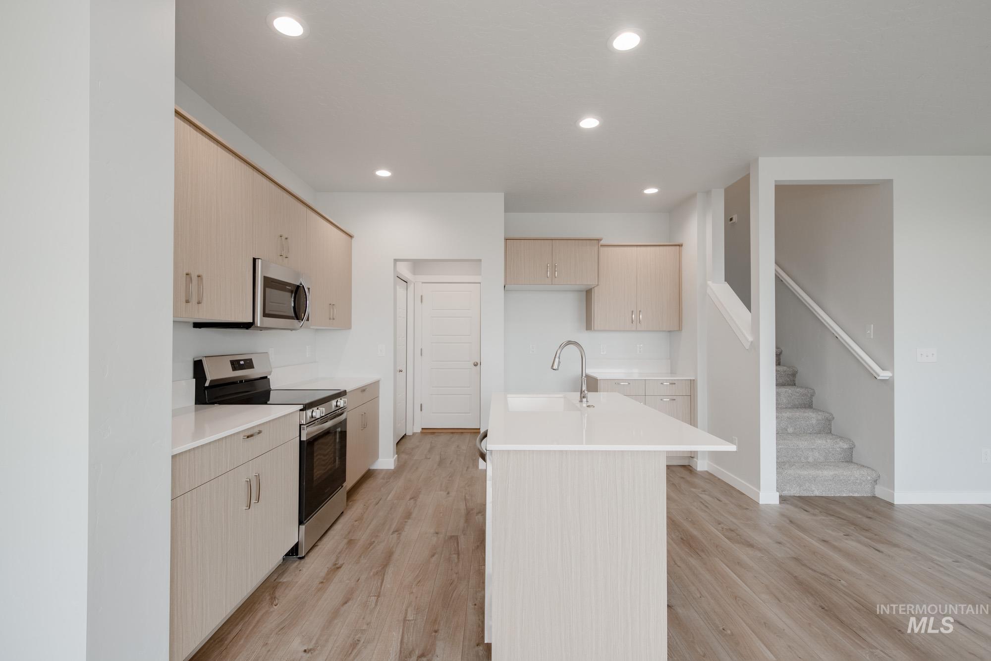 4155 North Delphi Avenue Meridian, ID 83646 - Photo 9 of 24 Kitchen with appliances with stainless steel finishes, light brown cabinets, recessed lighting, an island with sink, and light wood-style flooring