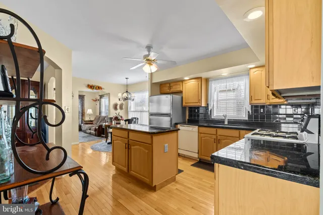 a kitchen with stainless steel appliances granite countertop a refrigerator a sink dishwasher a stove and white countertops with wooden floor