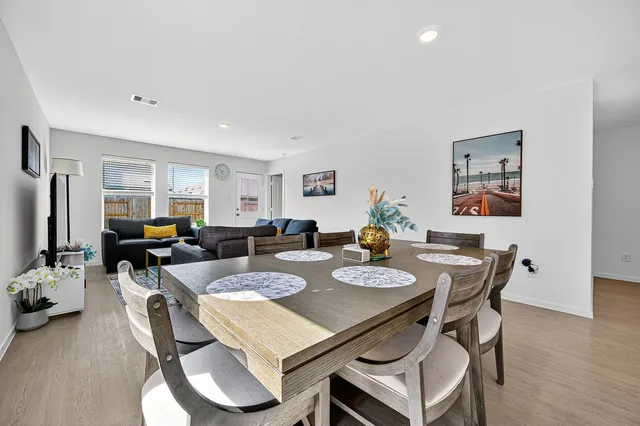 a view of a dining room and livingroom with furniture a rug a painting and a chandelier