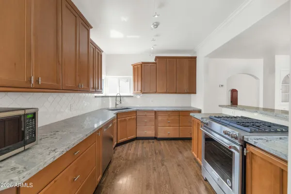 a kitchen with stainless steel appliances granite countertop a stove a sink and a microwave