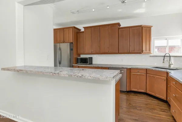 a kitchen with stainless steel appliances granite countertop a sink a stove and a refrigerator with wooden cabinets