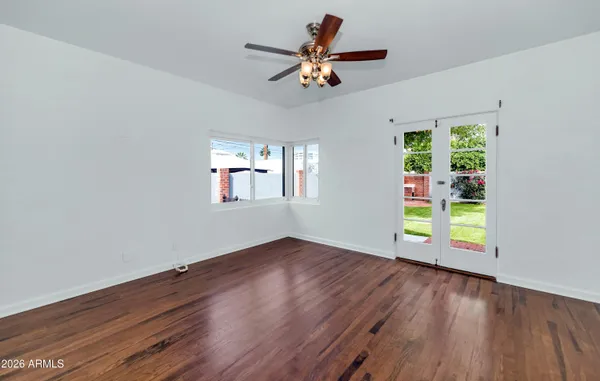 a view of an empty room with a window and wooden floor