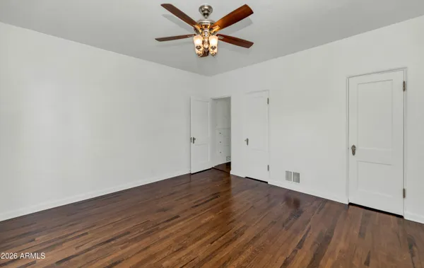 an empty room with wooden floor and a ceiling fan