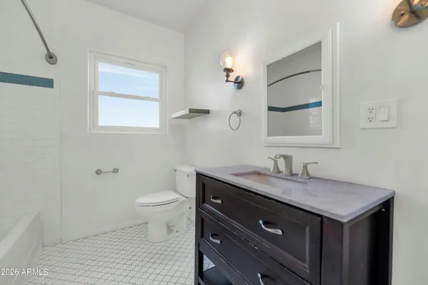 a bathroom with a granite countertop toilet sink and mirror