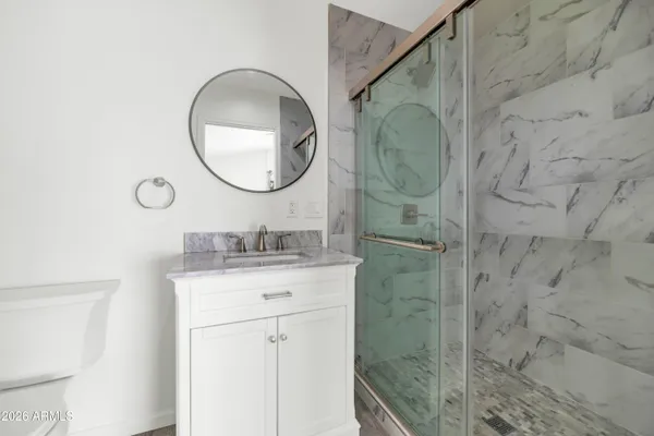 a bathroom with a granite countertop shower a mirror and a sink