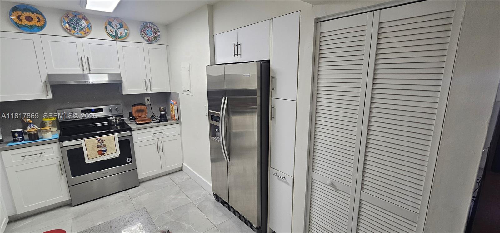 14921 Southwest 82nd Lane, Unit 19508 Miami, FL 33193 - Photo 6 of 31 a kitchen with a refrigerator and white cabinets