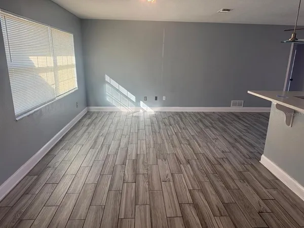 a view of an empty room with wooden floor and a window