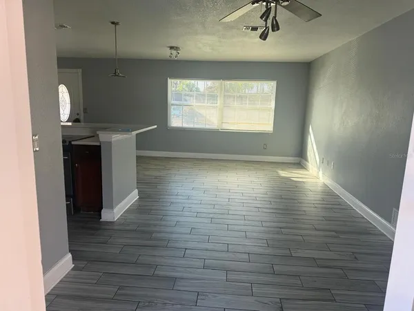 a view of kitchen and empty room with wooden floor
