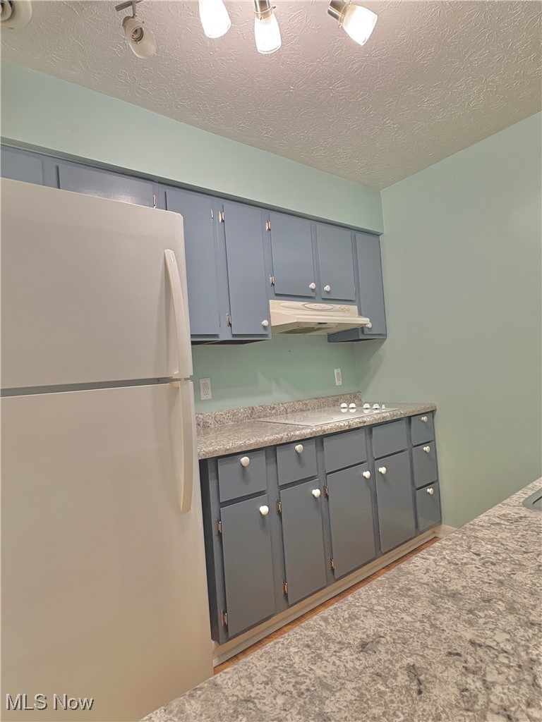 7050 Chillicothe Road, Unit C11 Mentor, OH 44060 - Photo 8 of 29 Kitchen featuring white appliances, a textured ceiling, light countertops, gray cabinetry, and under cabinet range hood