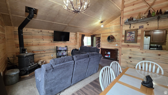 5782 Pineview Loop, Unit 921 Kamas, UT 84036 - Photo 11 of 29 Open-concept living space featuring wood-paneled walls, vaulted ceilings, and a prominent wood-burning stove with an exposed flue