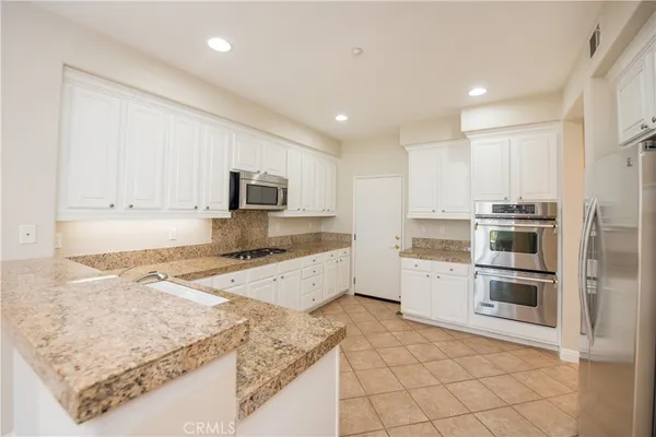 a kitchen with stainless steel appliances granite countertop a stove top oven a sink a counter space and cabinets