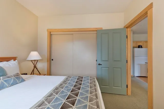 a bedroom with a bed and a lamp on the dresser