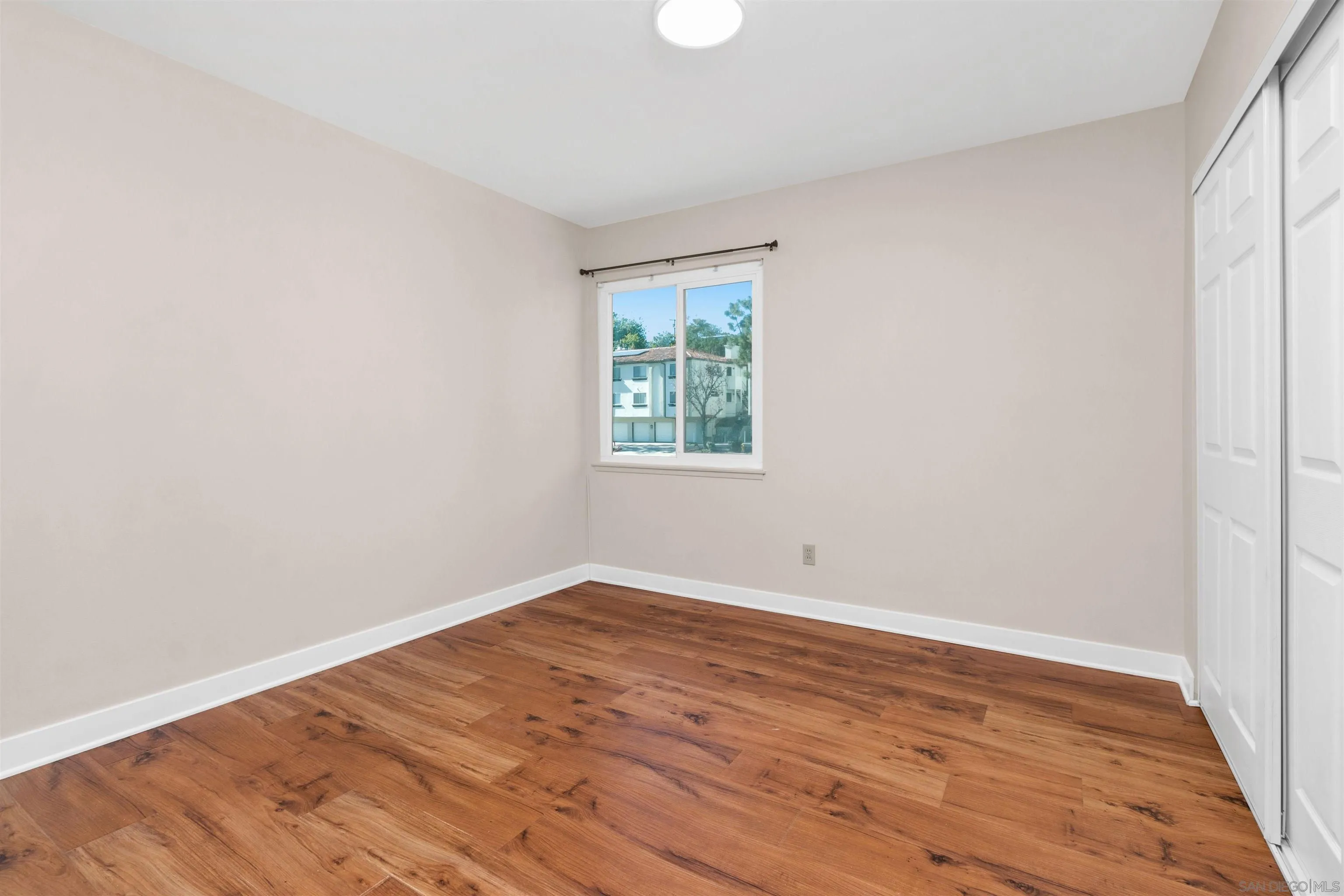 5685 Jackson Drive La Mesa, CA 91942 - Photo 19 of 24 an empty room with wooden floor and windows