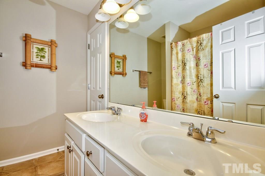 7754 San Gabriel Street Raleigh, NC 27613 - Photo 23 of 25 Full bath up has double sinks, a tub/shower and tile flooring.