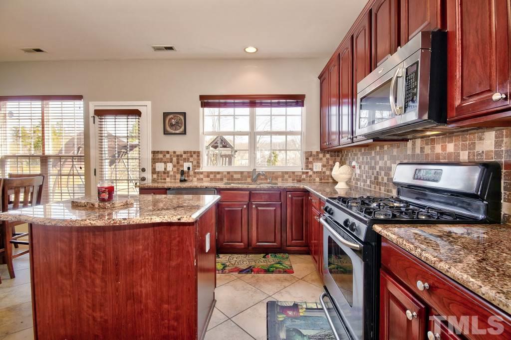 7754 San Gabriel Street Raleigh, NC 27613 - Photo 9 of 25 Spacious kitchen includes an island with granite, stunning cabinets, ss appliances, tile back splash, pantry, gas stove! What more can I say? Fabulous kitchen?