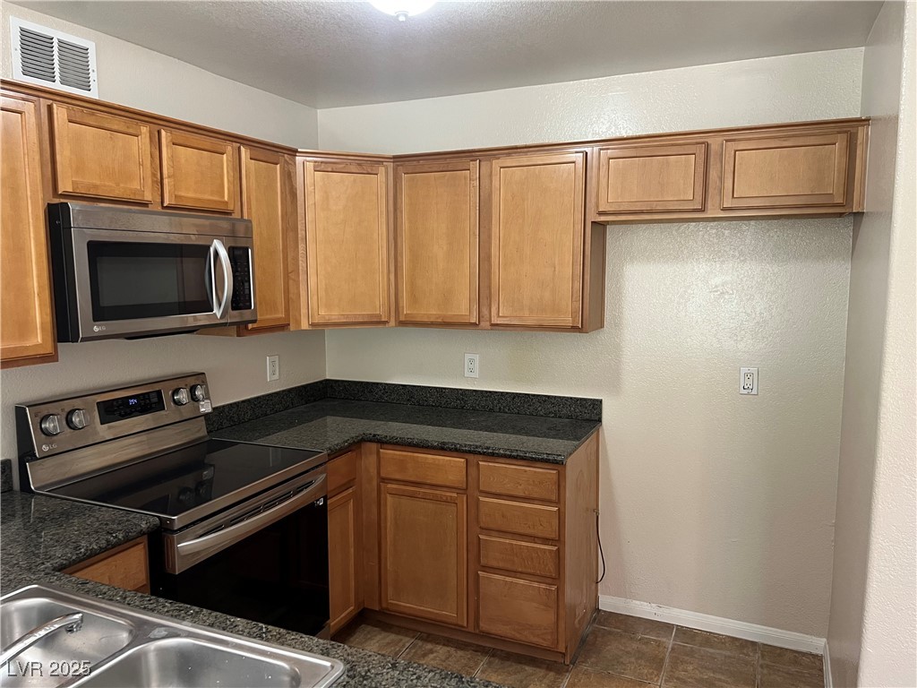 9325 West Desert Inn Road, Unit 233 Las Vegas, NV 89117 - Photo 4 of 10 Kitchen featuring appliances with stainless steel finishes, brown cabinetry, and a textured ceiling