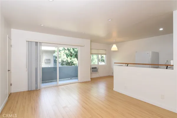a view of a room with wooden floor and a refrigerator