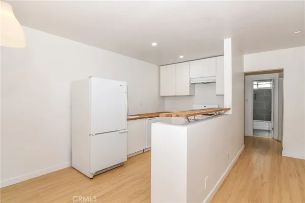 a kitchen with a refrigerator a stove top oven and wooden floor
