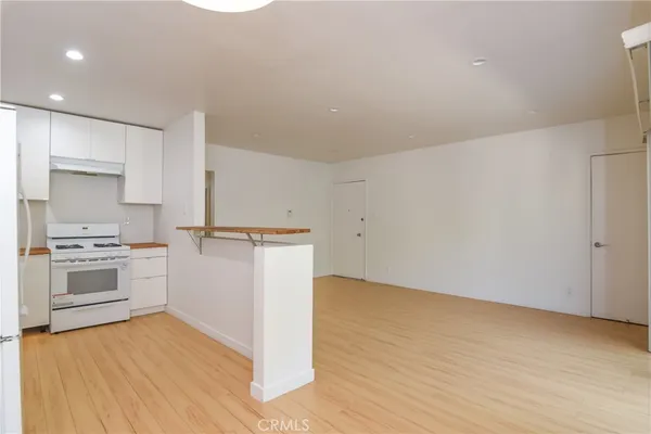 a kitchen with cabinets wooden floor and stainless steel appliances