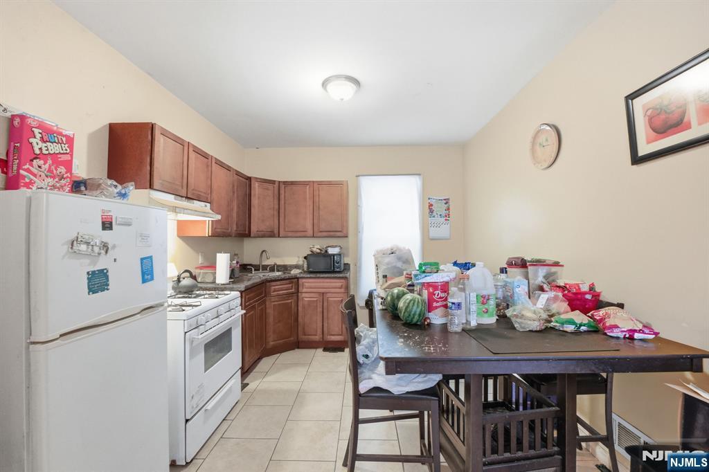 38 Mapes Avenue Newark, NJ 07112 - Photo 19 of 27 a kitchen with a dining table cabinets and stove top oven