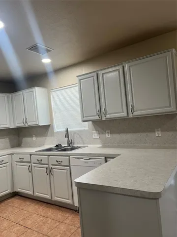 a kitchen with a sink dishwasher and white cabinets with wooden floor