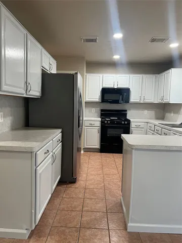 a kitchen with granite countertop a refrigerator and a stove top oven