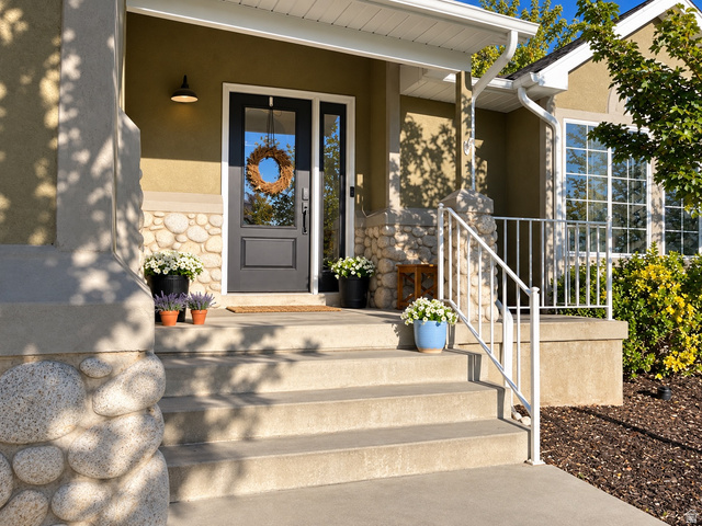12169 Hidden Valley Road, Unit 44 Sandy, UT 84092 - Photo 3 of 49 Welcoming entry featuring a dark-paneled door, sidelight window, stone façade accents, concrete steps, and white metal railing