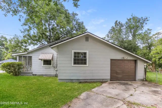 a front view of house with yard and trees in the background