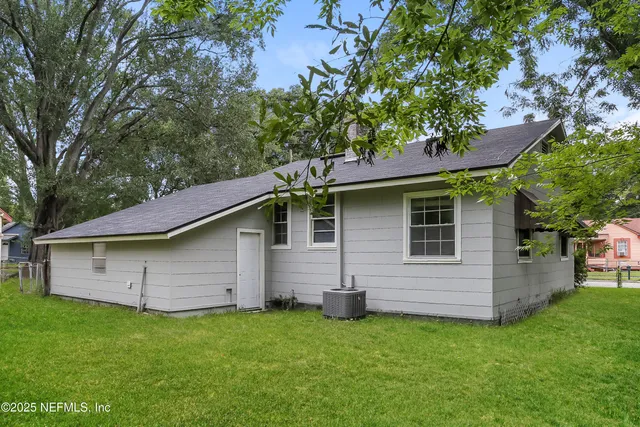 a backyard of a house with potted plants and a large tree