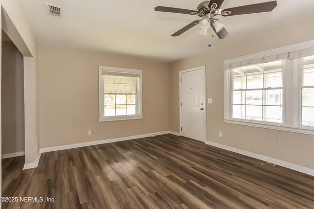 a view of an empty room with wooden floor and a window