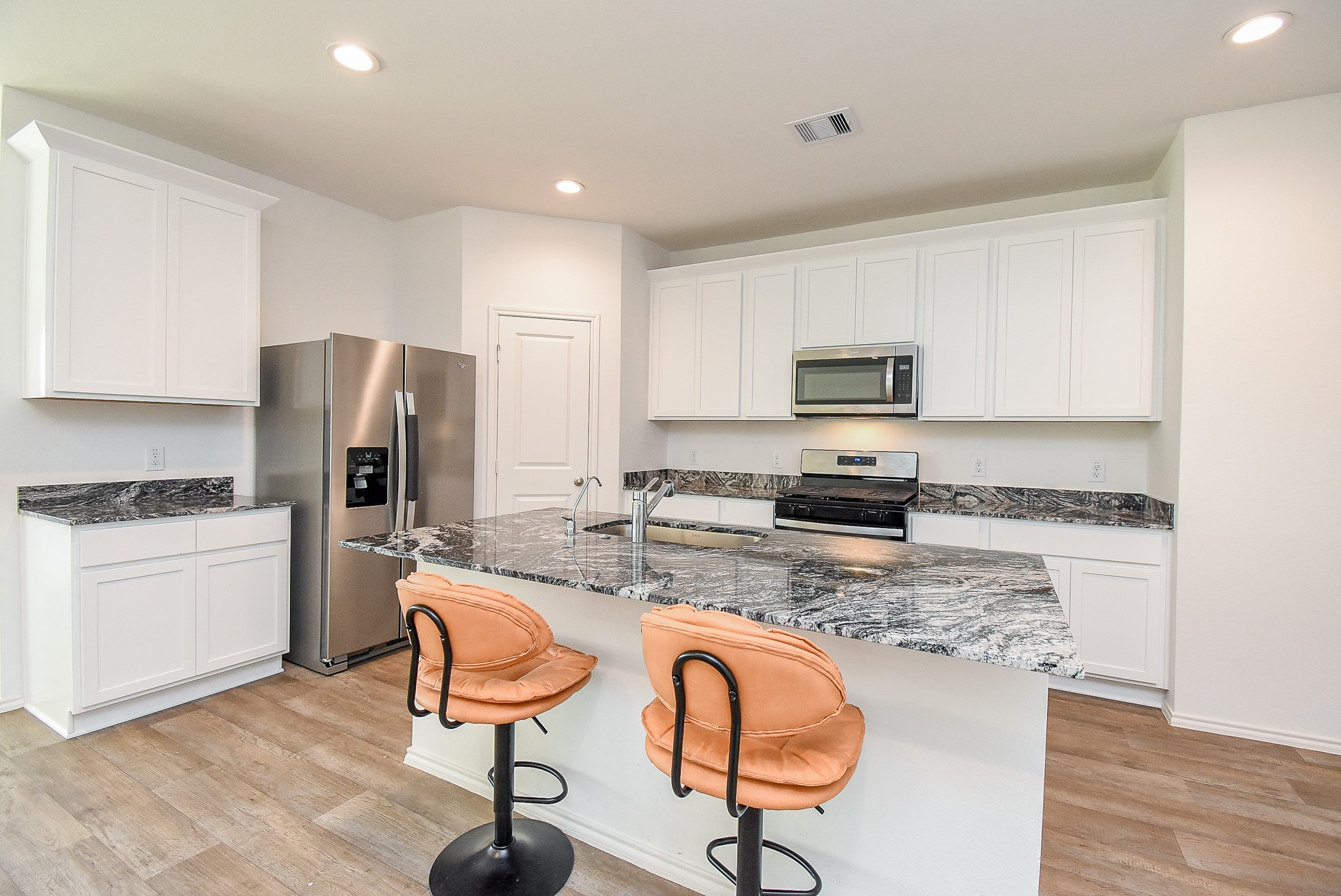 2827 Bur Lndg Lane Rosenberg, TX 77469 - Photo 11 of 20 a kitchen with stainless steel appliances granite countertop a stove a refrigerator a sink a dining table and chairs with wooden floor